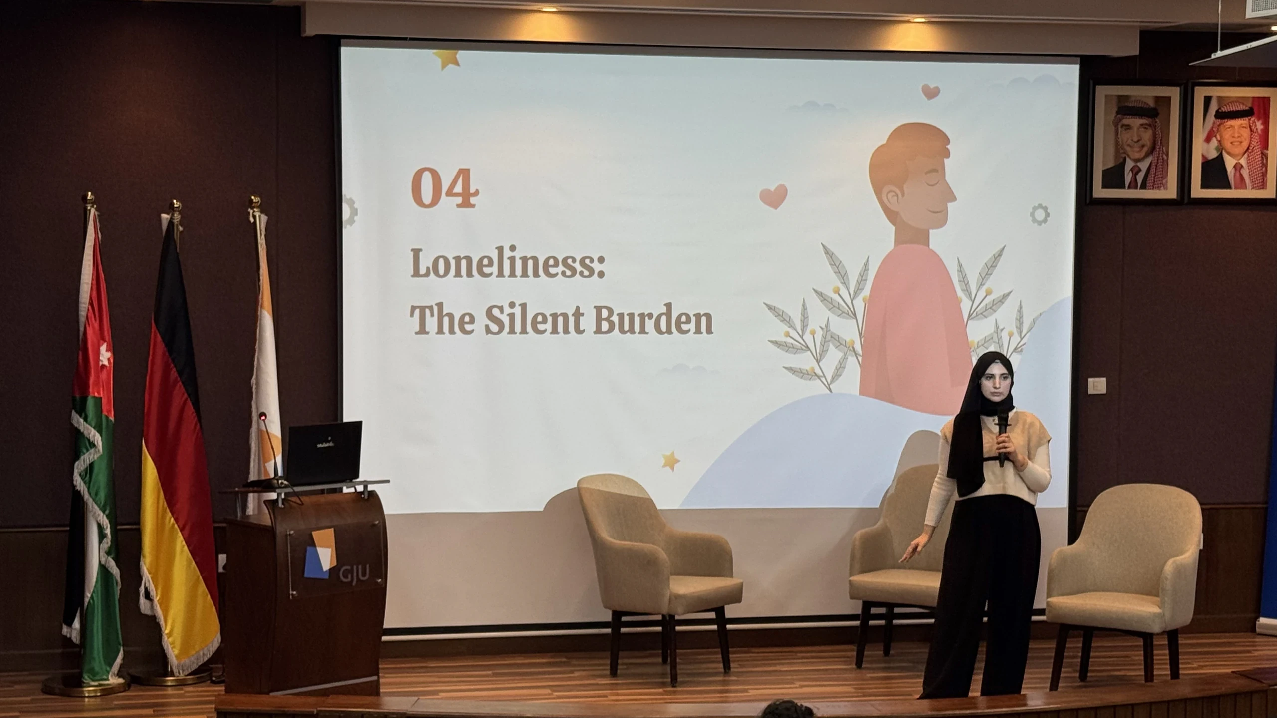 A student presenter speaking in front of a projected slide