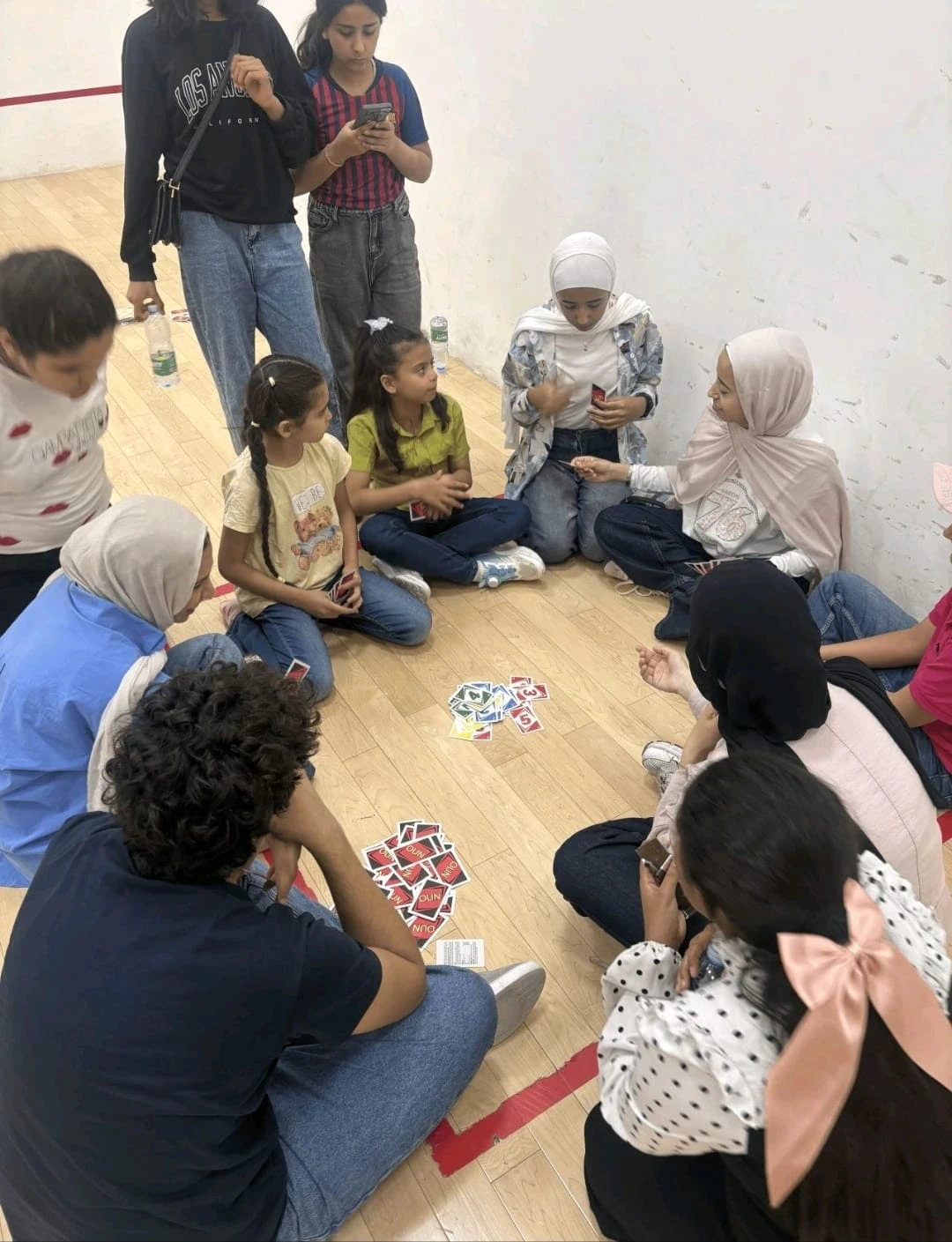 A group seated in a circle on an indoor court during a card activity